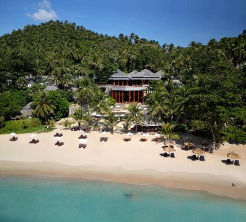 a beach with palm trees and palm trees at The Surin Phuket - SHA Extra Plus in Surin Beach