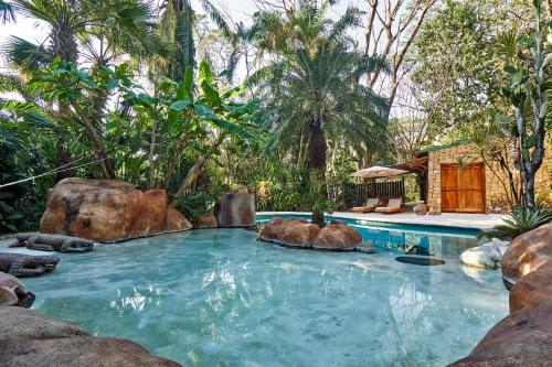 a swimming pool in a resort with rocks and trees at Villa Havana in Mal País