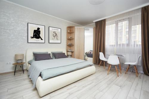 a white bedroom with a bed and a table and chairs at Apartments Club Marine in Odesa