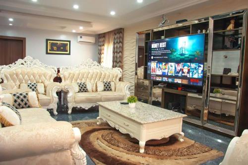 a living room with white furniture and a flat screen tv at Modern Luxury Home W/ 24H Power Wi-Fi & Security in Abuja