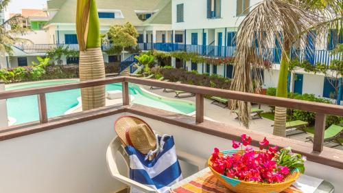a balcony with a table and a basket of flowers at Leme Bedje - Pool, WiFi & Beachfront in Santa Maria