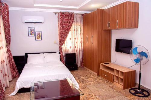 a bedroom with a bed and a tv and a table at Modern Luxury Home W/ 24H Power Wi-Fi & Security in Abuja