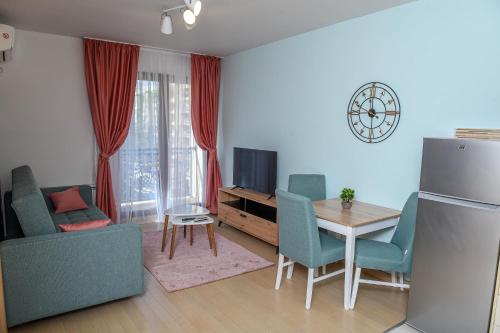 een woonkamer met een tafel en stoelen en een televisie bij Flatiron Apartments Skopje in Skopje