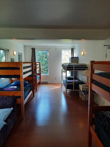 a room with three bunk beds and a room with a hallway at C&N Backpackers - Ucluelet in Ucluelet