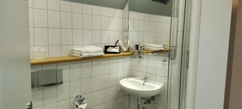 a white tiled bathroom with a sink and a mirror at Bed and Breakfast Wehlen in Stadt Wehlen