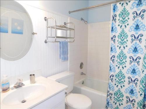 Un baño con lavabo, inodoro y cortina de ducha. en S3, comfy, close to pickleball, en Mallory Park