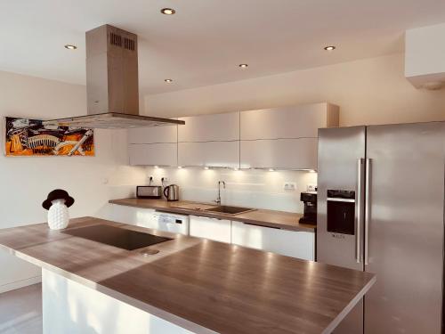 a kitchen with white cabinets and a stainless steel refrigerator at Villa bord de mer in Le Grau-dʼAgde