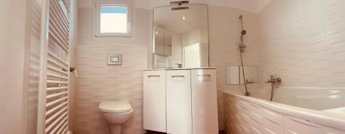 a white bathroom with a toilet and a sink at Villa bord de mer in Le Grau-dʼAgde