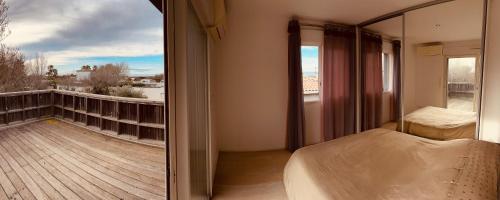 a bedroom with a balcony with a bed and a window at Villa bord de mer in Le Grau-dʼAgde