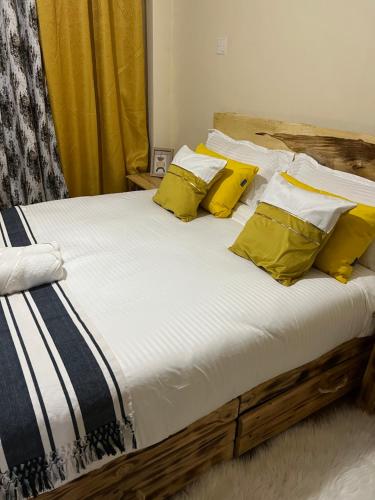 uma cama com lençóis e almofadas amarelos e brancos em Fully Furnished 2br Apartment King'ong'o Nyeri - Youngsky em Nyeri