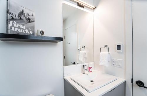 a white bathroom with a sink and a mirror at Switchback Suite by Revelstoke Vacations in Revelstoke