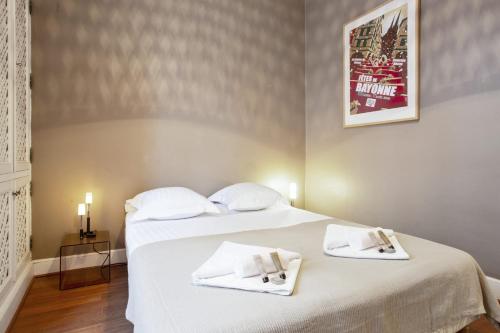 une chambre avec un lit avec des draps blancs et des serviettes dans l'établissement Appartement Ampalia - Welkeys, à Biarritz