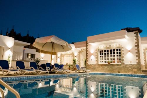 een zwembad met stoelen en een parasol bij Villa golden life apartments, new property with pool access in Luxor
