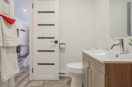 Łazienka z białą toaletą i umywalką w obiekcie Motel Champlain w mieście Brossard