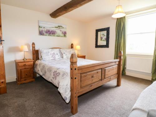 a bedroom with a wooden bed and a window at Mill Farm - The Farmhouse in Derby