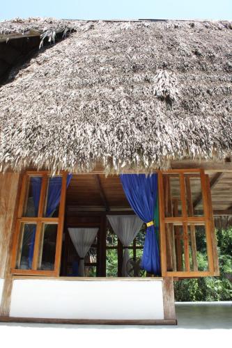 a building with windows and a straw roof at Posada del Cerro in El Remate