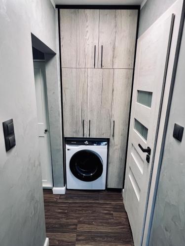 a washer and dryer in a room with wooden cabinets at Apartment of Love in Olecko