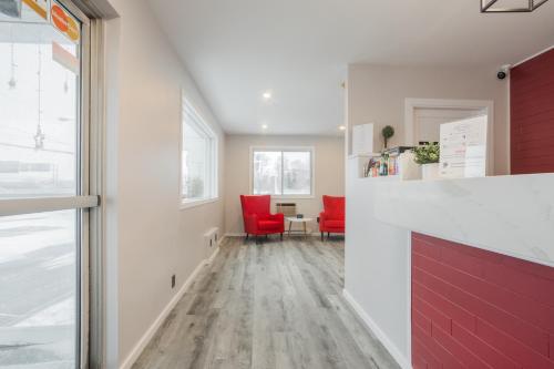 - un couloir avec des chaises rouges et une table dans la chambre dans l'établissement Motel Champlain, à Brossard