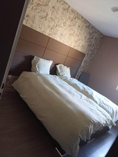 une chambre avec un grand lit avec des draps et des oreillers blancs dans l'établissement Appartement Gauche avec balcon, à Hargarten-aux-Mines