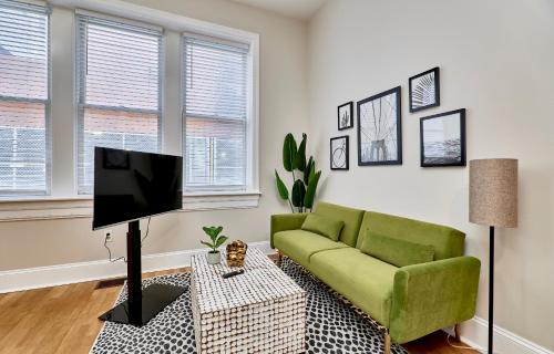 a living room with a green couch and a tv at White House at Grand Central in Tower Grove