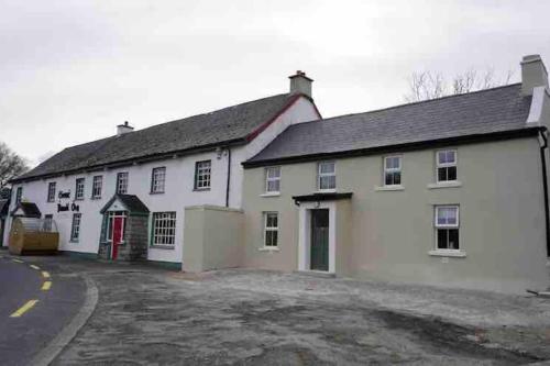 a white building with a red door next to a street at Stunning riverside cottage in central location in Donegal