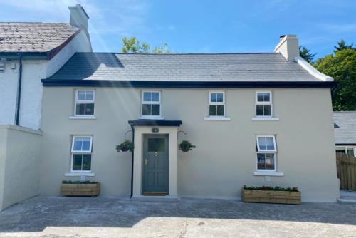 a white house with a green door at Stunning riverside cottage in central location in Donegal