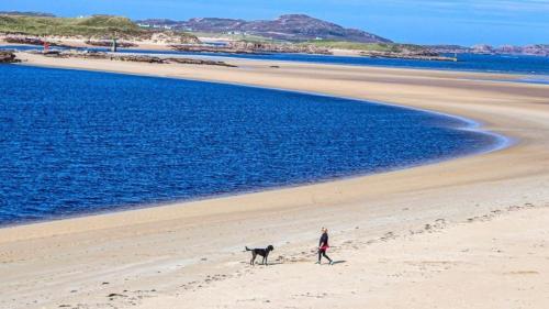 a person walking a dog on the beach at Stunning riverside cottage in central location in Donegal