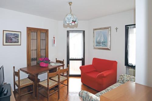 een woonkamer met een rode stoel en een tafel bij Al lago Guest House in Revine Lago