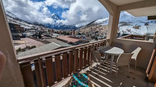 balcón con mesa, sillas y vistas a la montaña en Au pied des pistes avec panorama sur les montagnes en Les Deux Alpes