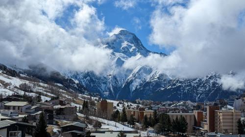 una montaña cubierta de nieve en el fondo de una ciudad en Au pied des pistes avec panorama sur les montagnes en Les Deux Alpes