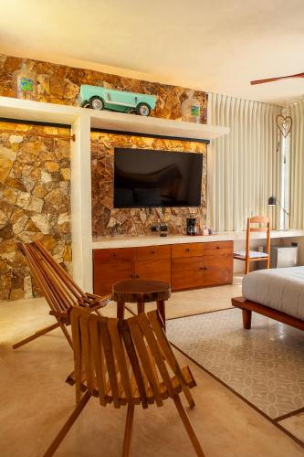 a living room with a tv on a stone wall at La Parcela Cunkal in Conkal
