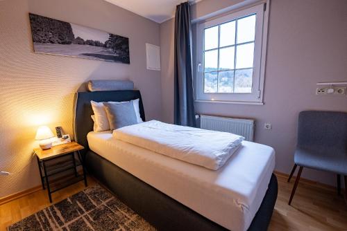 a small bedroom with a bed and a window at Hotel Fronhof Mettendorf in Mettendorf