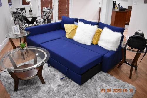 a blue couch with yellow pillows and a glass table at Lovely private one bedroom apartment in Kanata in Ottawa