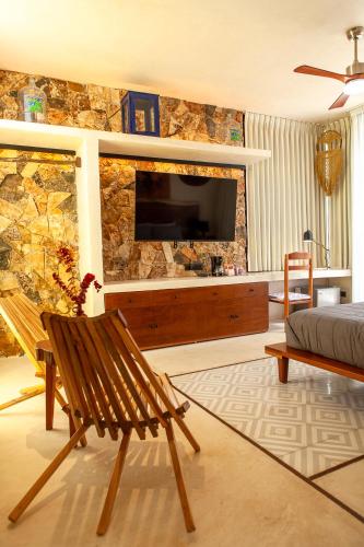 a living room with a television on a stone wall at La Parcela Cunkal in Conkal