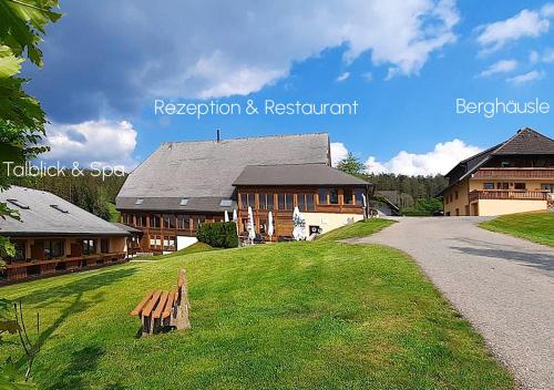 a building with a bench in the grass next to a road at ThälerHäusle in Furtwangen
