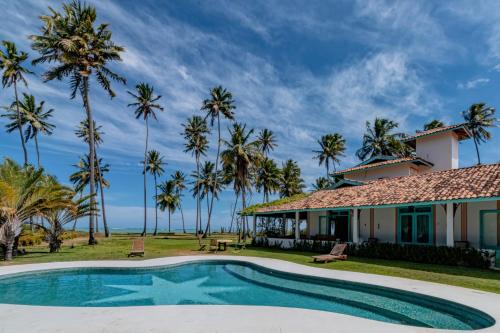 ein Haus mit einem Pool und Palmen in der Unterkunft Casa Brasileira - Hotel Galeria in Pôrto de Pedras