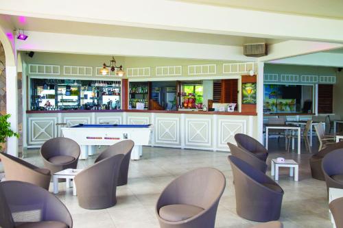 a restaurant with a bar with chairs and a counter at Hôtel Bois Joli in Terre-de-Haut