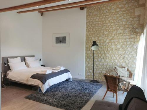 een slaapkamer met een bed en een stenen muur bij Chez Foucherie in Nonac