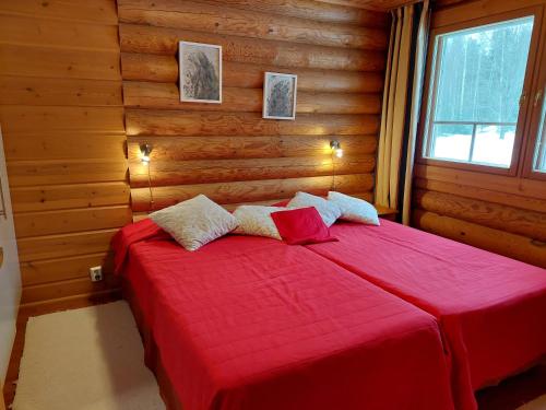 1 dormitorio con 1 cama roja en una cabaña de madera en Ollinmäki Vineyard en Anttola