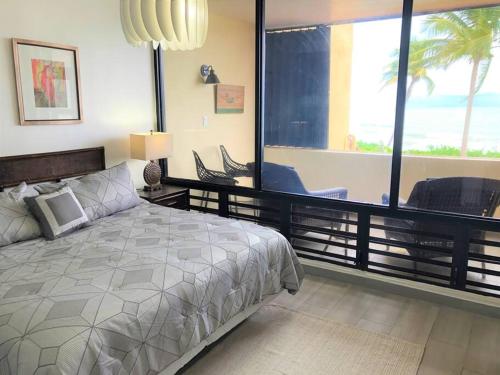 ein Schlafzimmer mit einem Bett und einem großen Fenster in der Unterkunft Beachfront Getaway for two! in Humacao
