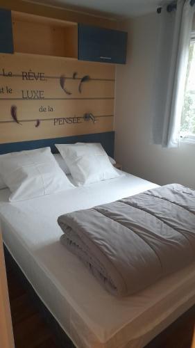 1 dormitorio con 1 cama con sábanas blancas y ventana en Mobilhome proche du Puy du Fou en La Boissière-de-Montaigu