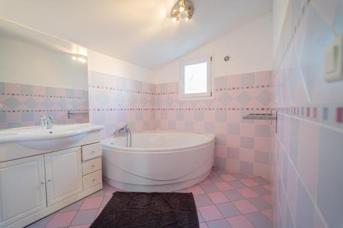 een roze en witte badkamer met een bad en een wastafel bij L'ALIVETTE in Bastelicaccia
