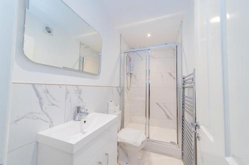 a white bathroom with a sink and a shower at MORDEN STUDIO CENTRAL BRIGHTON LOCATION Sleep 3 Guests in Brighton & Hove