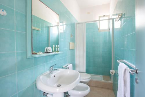 bagno blu con lavandino e servizi igienici di Villaggio Club In a Vieste