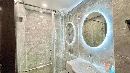 Un baño con lavabo y ducha con espejo. en LAD Apartment & Homestay Hải Phòng - Hoàng Huy Grand Tower, en Hai Phong