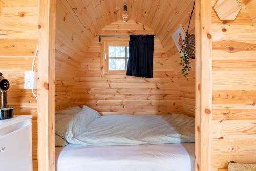 a bed in a log cabin with a window at Tiny Camping Pod in Warmond