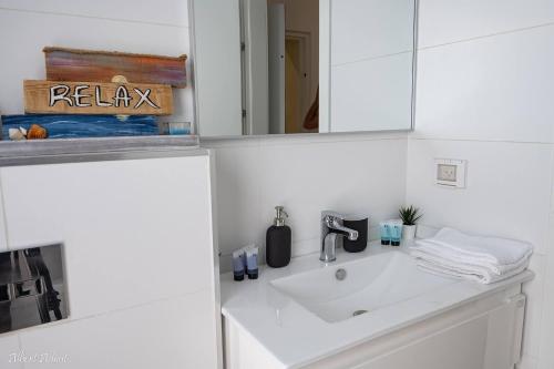 a white bathroom with a sink and a mirror at Paradise in Achziv Beach in Nahariyya
