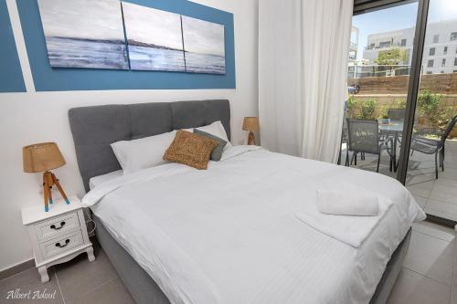 a bedroom with a large white bed and a balcony at Paradise in Achziv Beach in Nahariyya