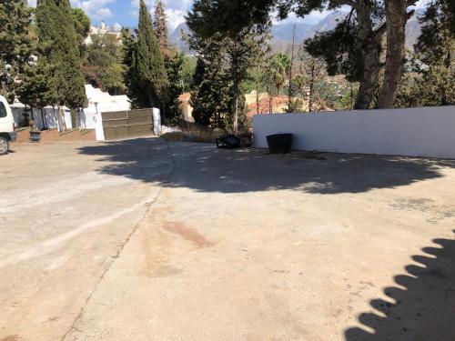 a concrete parking lot with a white fence and trees at Villa Carmen in Nerja