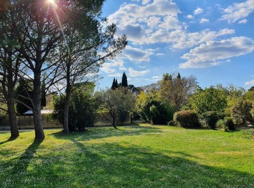 a park with green grass and trees and the sun at Aux berges du pont du gard in Vers Pont du Gard